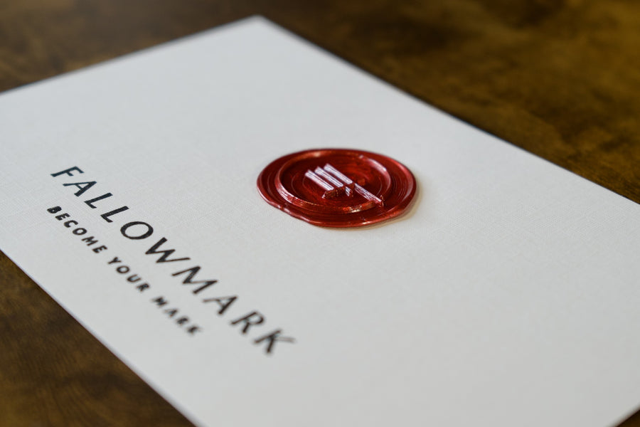 A Fallowmark card with a red wax seal lying on a wooden desk